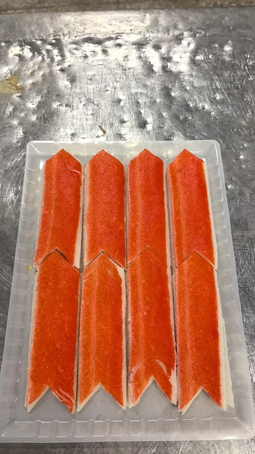 A tray of orange and white oblique-cut crab stick samples